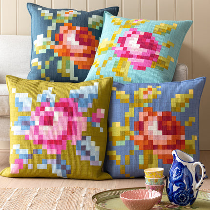 Four colorful floral-patterned cushions on a couch with a small table and decorative items.