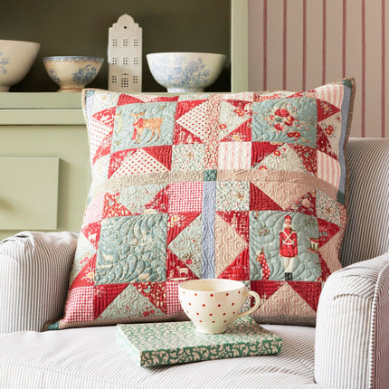 Patchwork pillow on a sofa with decorative plates and bowls in the background