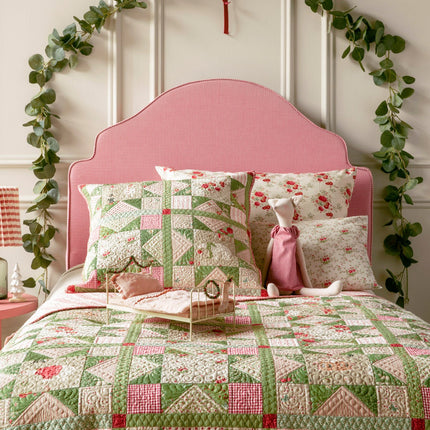 Bedroom with pink headboard, floral bedding, and decorative greenery.